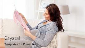  Presentation with motherhood - Theme consisting of motherhood pregnancy people and kids clothing concept - happy woman holding and looking at pink baby girls bodysuit at home background and a soft green colored foreground