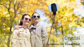  Presentation with friendship - Slide deck enhanced with people children friendship and season concept - happy girls taking picture with smartphone on selfie stick over autumn park background background and a yellow colored foreground
