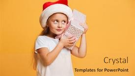  Presentation with girl christmas - PPT theme having picture of little concentrated girl standing isolated over yellow background wearing christmas santa hat looking aside holding surprise gift box background and a yellow colored foreground