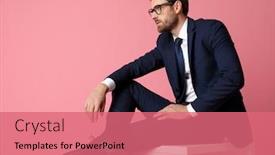  Presentation with business pink - PPT theme having side view of a young formal business man in navy suit with glasses sitting and resting his hands on his laps and his leg on the chair while looking away pensive on pink studio background background and a coral colored foreground