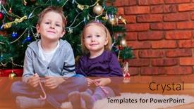  Presentation with christmas kids - PPT theme consisting of two small kids at home sitting near beautifully decorated christmas tree background and a red colored foreground