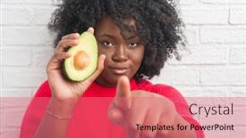  Presentation with white brick wall - Slides enhanced with young african american woman over white brick wall eating avocado pointing with finger to the camera and to you hand sign positive and confident gesture from the front background and a coral colored foreground