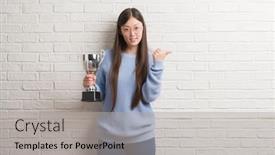  Presentation with trophy - Audience pleasing slide deck consisting of young chinese woman holding trophy pointing and showing with thumb up to the side with happy face smiling backdrop and a light gray colored foreground