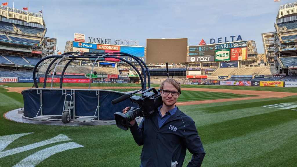 camera person holding camera on baseball field
