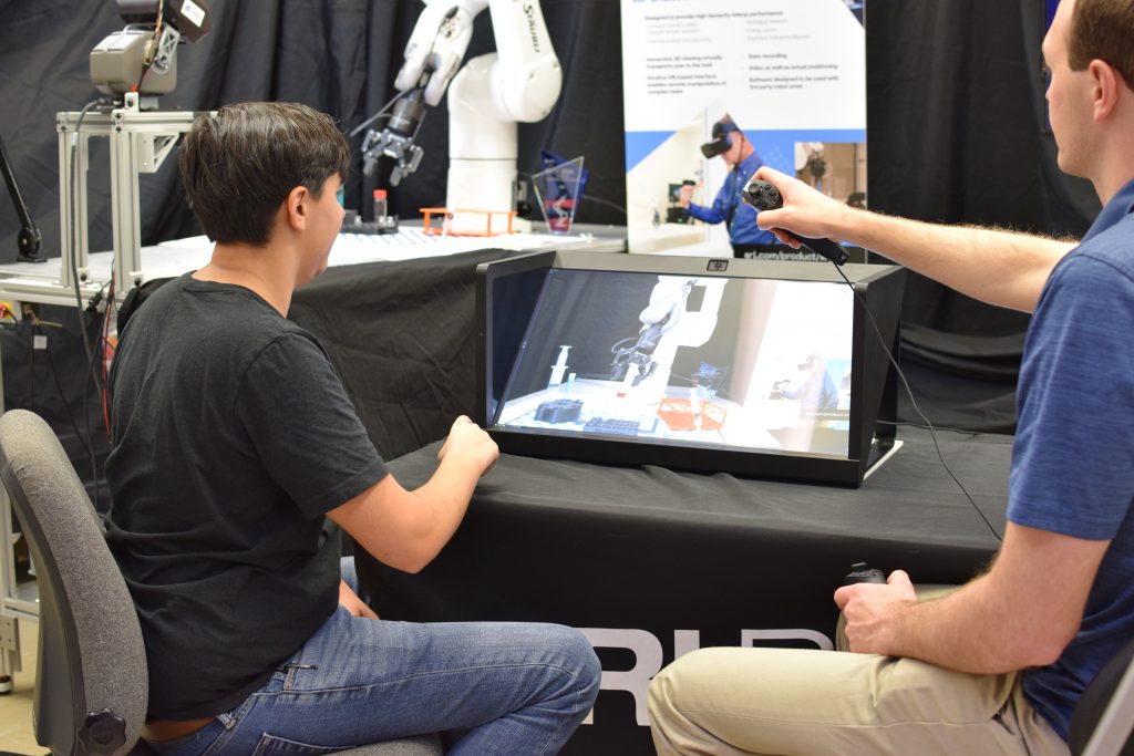 people looking at 3d display with robotic arm in back
