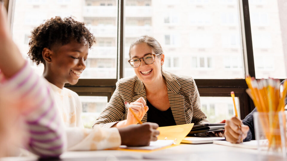 Teacher smiling as they work with student