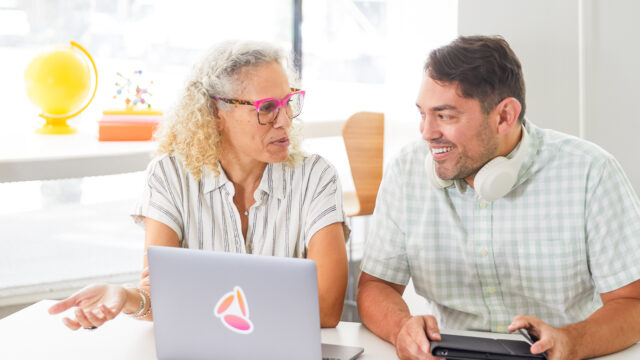 Two educators talking with a laptop open in front of them