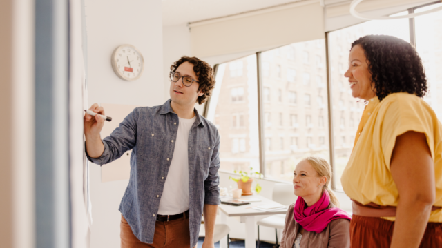 Teachers in a classroom participating in professional development at a whiteboard