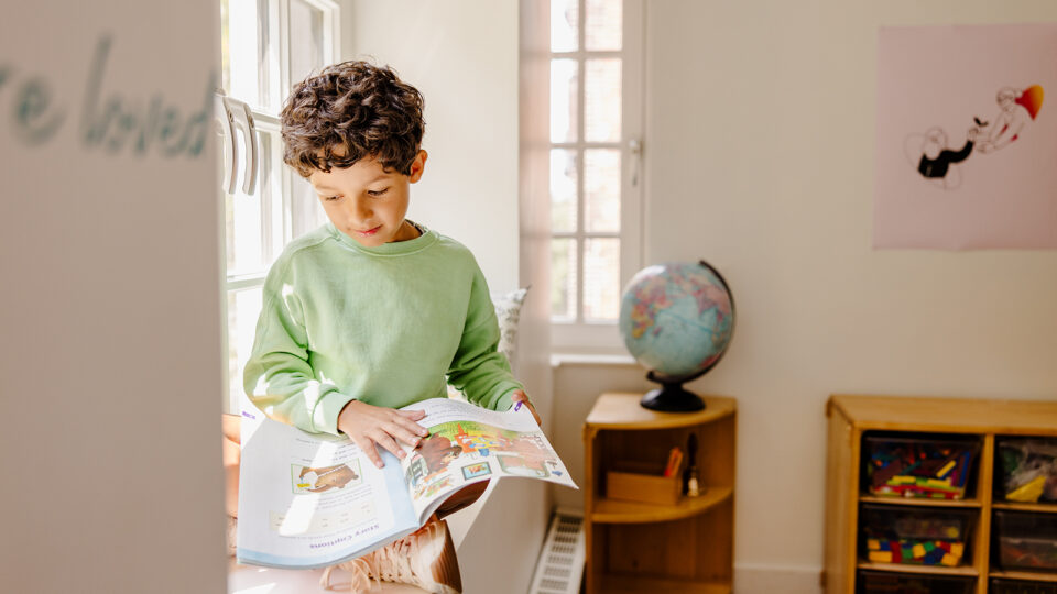 Young student reads a workbook while sitting by a window