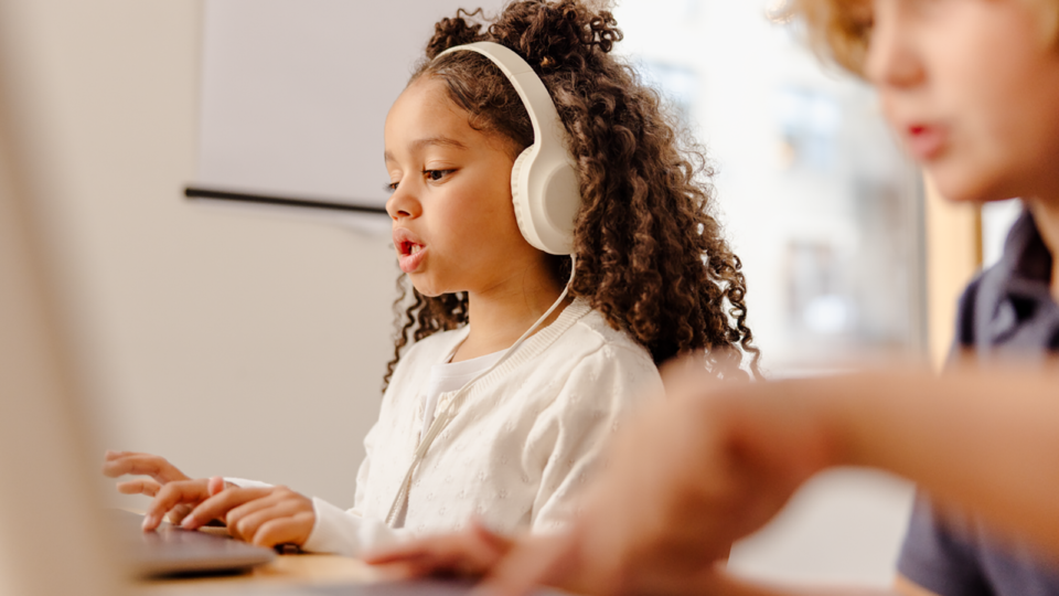 Young student wearing headphones completing a digital dyslexia screening on a computer