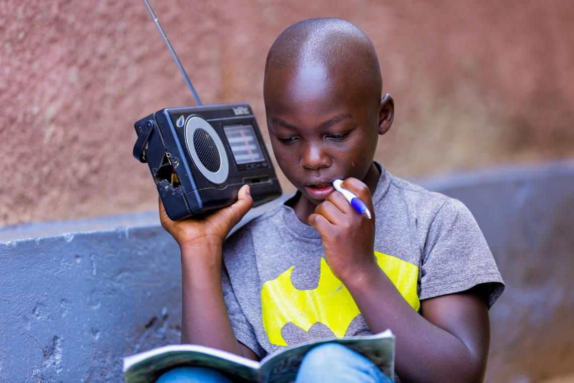 Igihozo, 11, listens to a lesson on the radio after his school was closed in Rwanda. Image Credit: UNICEF/UNI319836/Kanobana<br>