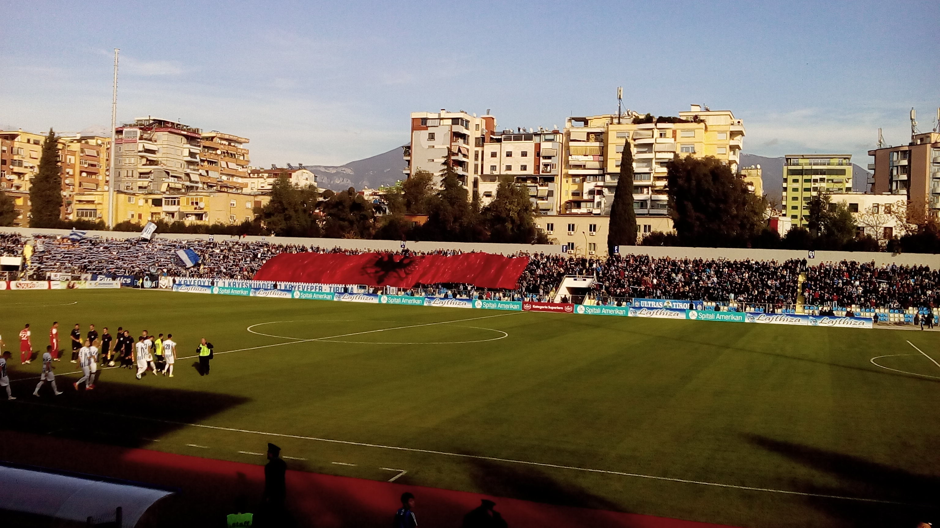 Les joueurs du FK Tirana (en blanc) rejoignant la pelouse par Sadsadas - Wikimédia Commons CC BY-SA 4.0
