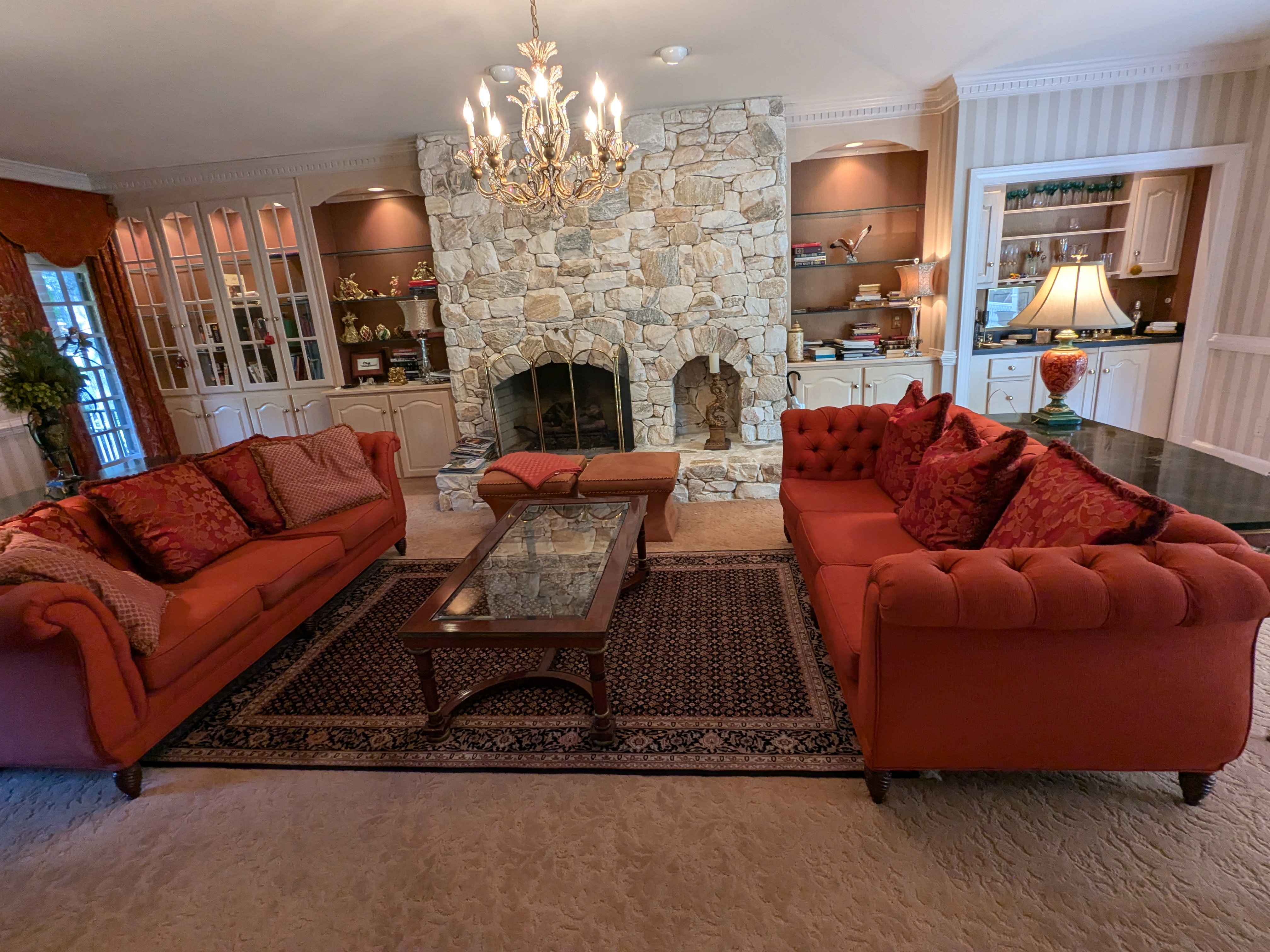 Living room with stone fireplace, red sofas and crystal chandelier at the Barrington estate sale in Short Pump, Henrico, VA