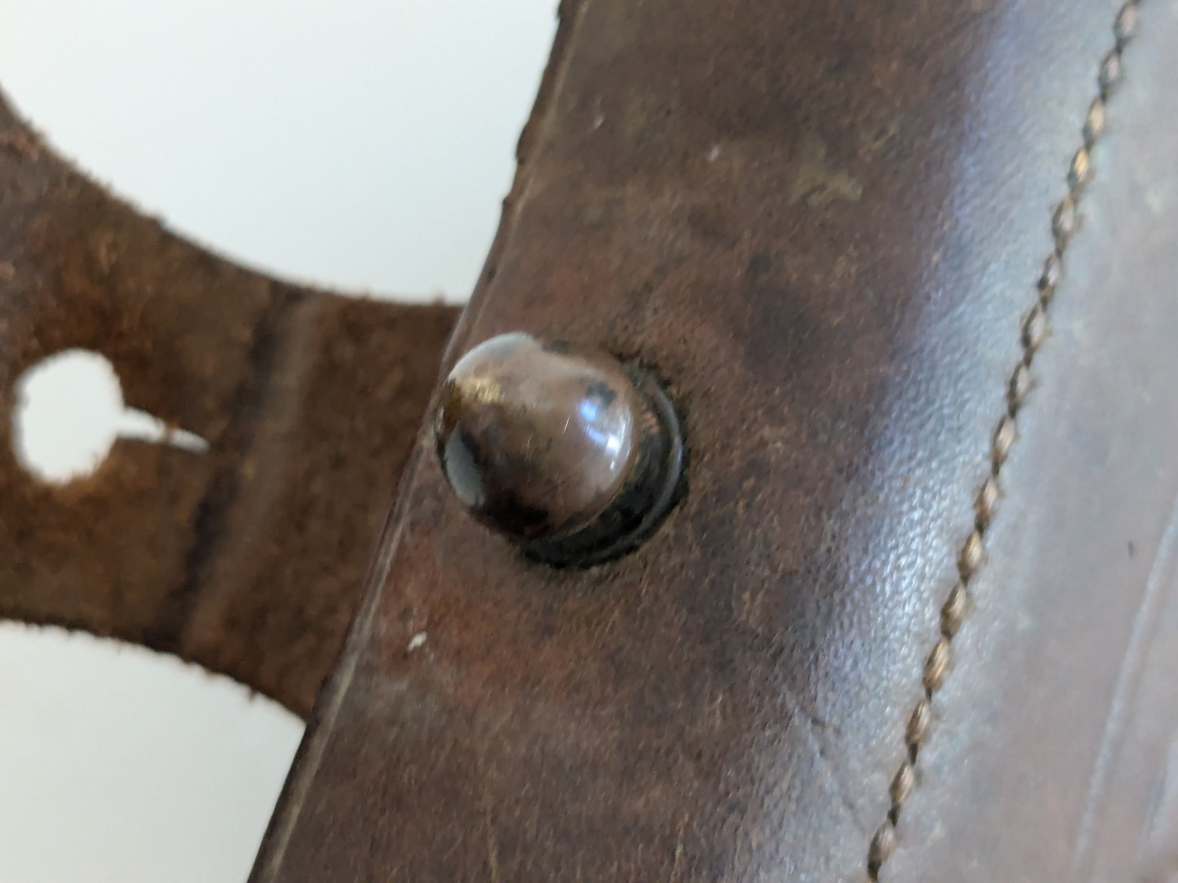 Close-up of a brass stud on a worn leather strap