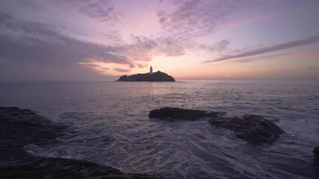 Beautiful sunset waves rocks at Godrevy Lighthouse, Cornwall, UK