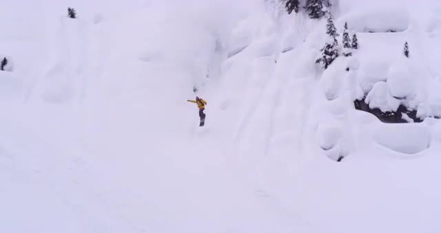 Wide shot of snowboarder riding down mountain