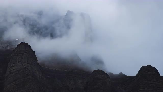 Moody long shot time lapse of clouds flowing through mountain peaks