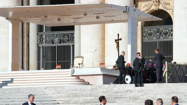 Bishops, security guards, priests, cardinals on stage, Vatican