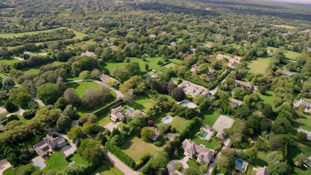 WIDE AERIAL POV over upscale neighborhood with large houses and swimming pools