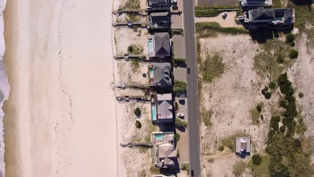 MEDIUM AERIAL OVERHEAD POV over houses along beach on Fire Island