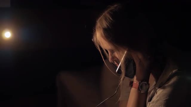 Woman in dark room talking on charging mobile