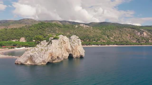 Separate rock Mingardo in the sea. Hilly coastline with long beach in sunny day. Campania, Italy
