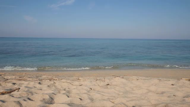 Sandy beach and gentle sea surf on sunny day. Crystal clear water