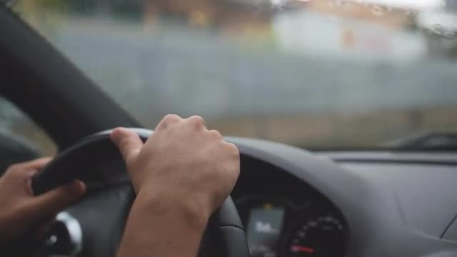 Driver hands on steering wheel. Driving in the rain. Windshield wipers remove water