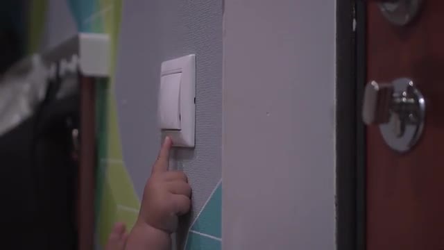 Baby turns off switch on a wall and lights go out. Close up shot of child's hand
