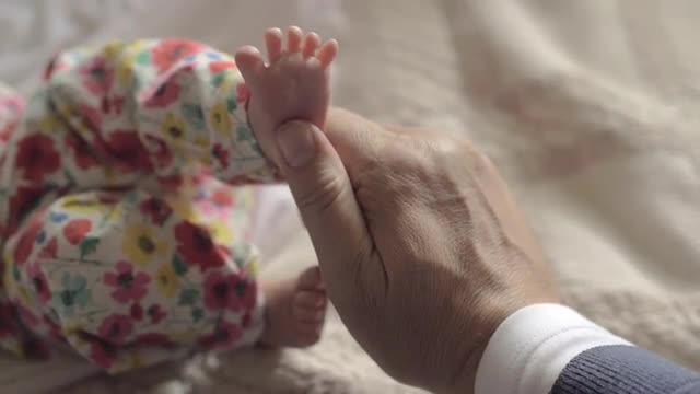 Grandad touching feet of baby grandchild