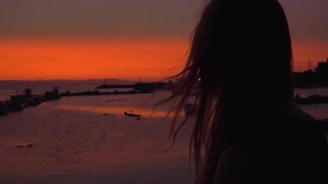 Lonely woman staring at small harbour in the evening