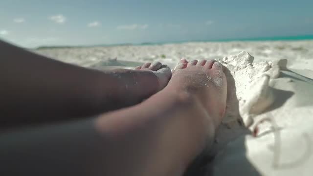 A woman's feet on the white sandy beaches of the Bahamas