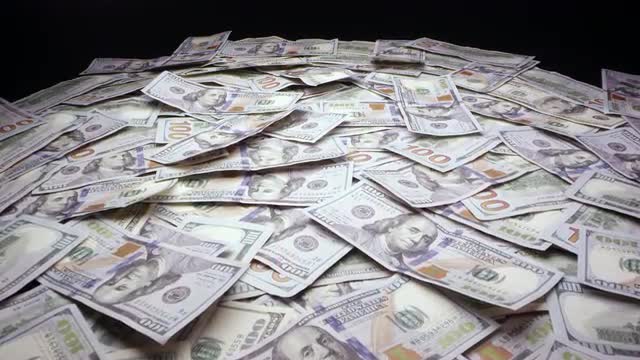 Moving over mountain of money viewing stack of 100 dollar bills