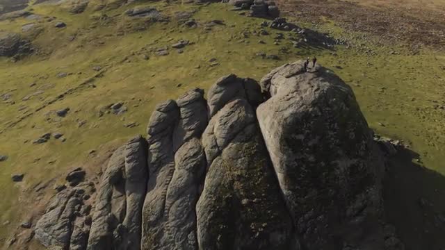 Drone shot of hikers standing atop mountain in beautiful green landscape