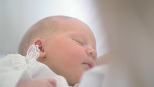 Newborn baby girl asleep in her mothers arms