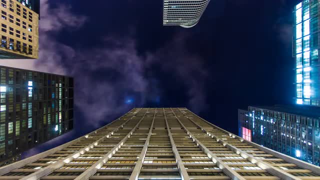 4K time-lapse of clouds and stars moving over highrise office buildings