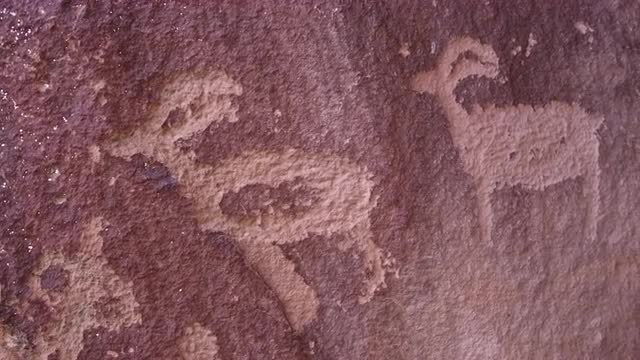 Panning view of petroglyphs on red rock in Utah