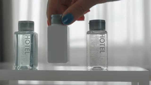 A closeup of three cosmetics bottles being put on a table