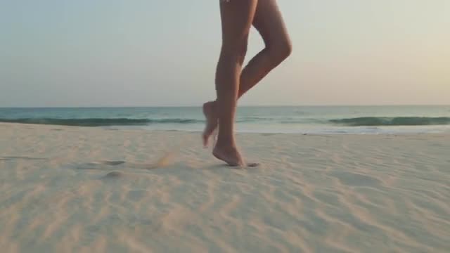 Female legs walking by beach