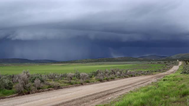 Time lapse looking down dirt road into dark shelf cloud storm moving