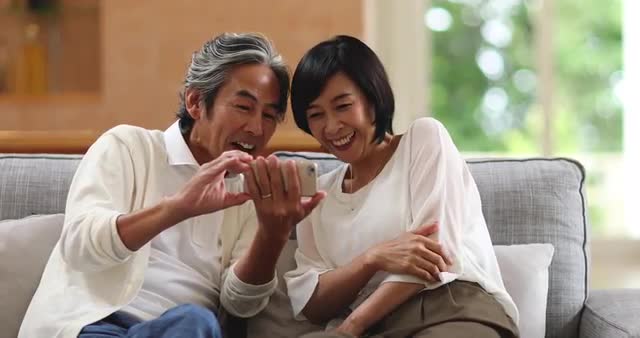 Japanese senior couple doing video call on the sofa