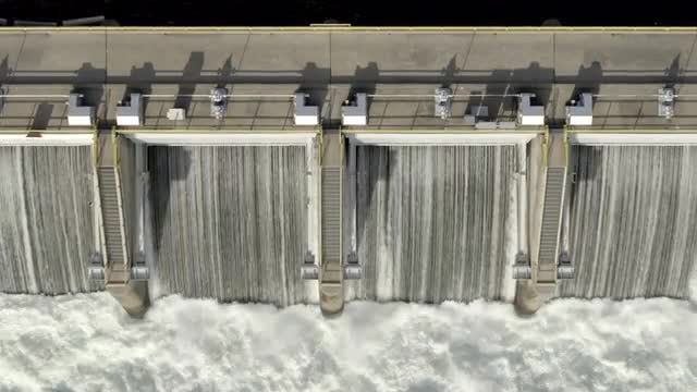 Medium aerial shot of water flowing over dam