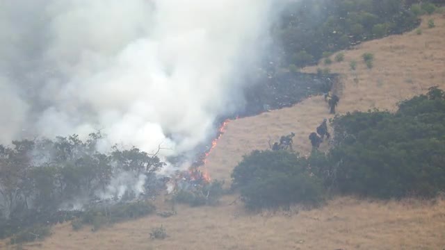 Wildfire burning on mountain as firefighters control the blaze