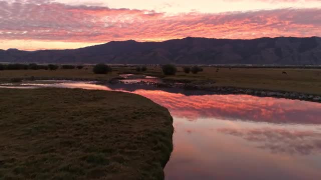 Aerial flying over winding river during sunrise