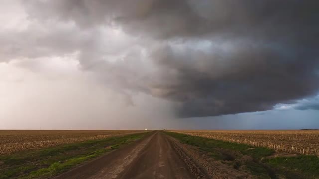 Looking down dirt road as storm clouds swirl in the sky