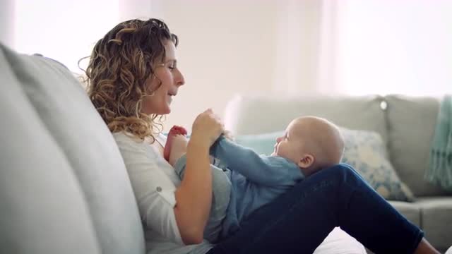 Mother happily plays with baby boy, moving his arms and smiling at him 8K