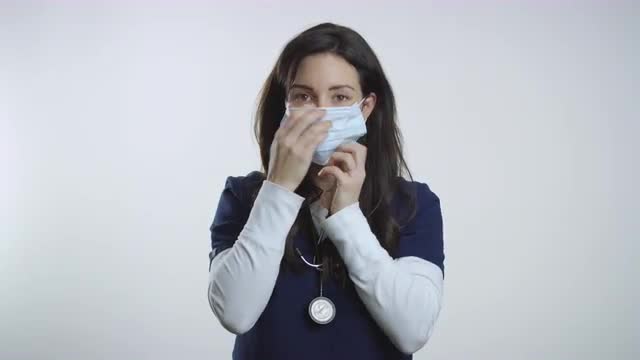 Nurse holds up mask and demonstrates how to put it on properly