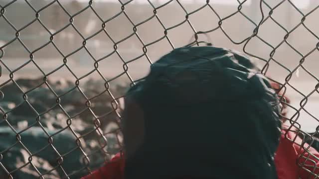 Person Crawling Through a Hole in a Chainlink Fence