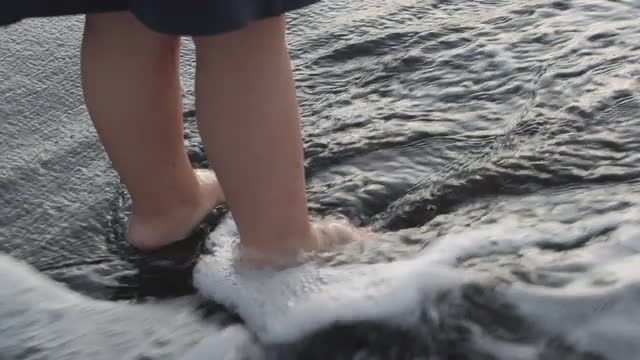 A slowmotion of waves washing childs feet
