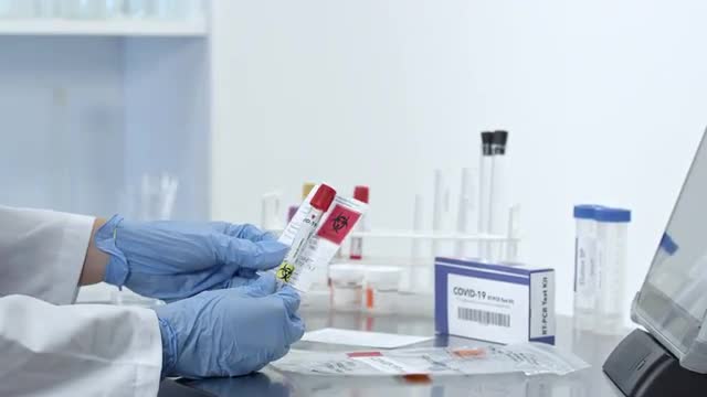 Woman lab technician adding swab test in tube and sealing